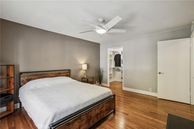 bedroom featuring hardwood / wood-style flooring, ceiling fan, and a walk in closet