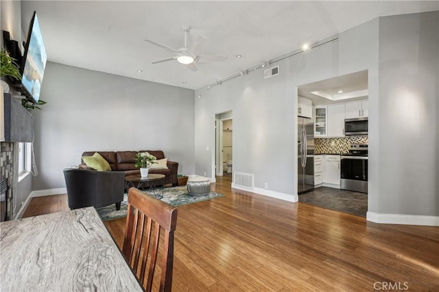 living room featuring ceiling fan, dark hardwood / wood-style flooring, and rail lighting