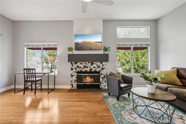 living room with a tile fireplace, ceiling fan, and hardwood / wood-style floors