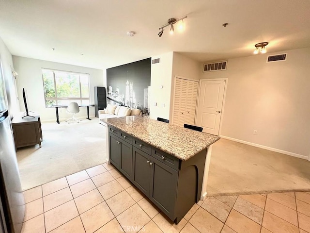 kitchen with kitchen peninsula, light stone countertops, and light colored carpet