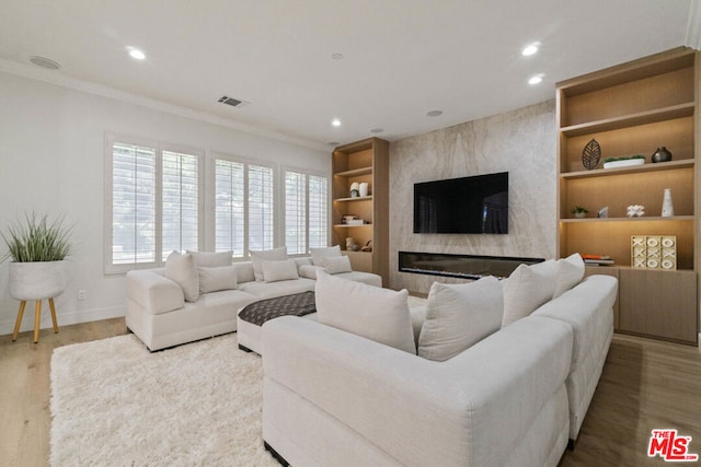 living room featuring light hardwood / wood-style floors, a premium fireplace, and crown molding