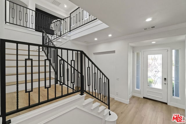 entrance foyer with light hardwood / wood-style floors and crown molding