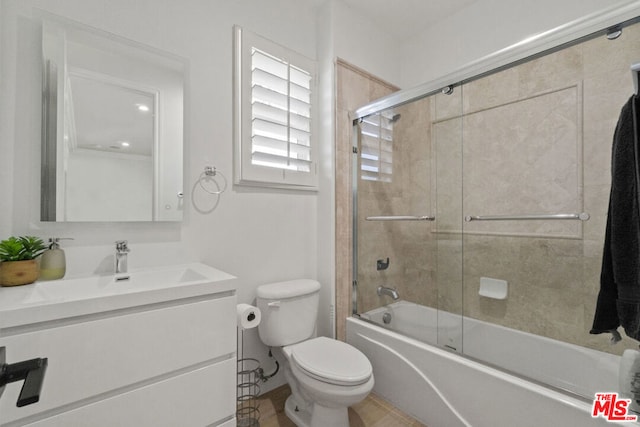 full bathroom featuring vanity, bath / shower combo with glass door, and toilet