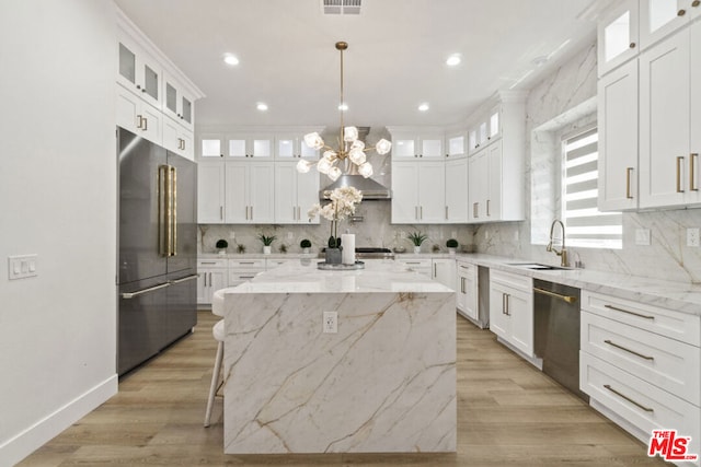 kitchen with white cabinets, a kitchen island, light stone countertops, and appliances with stainless steel finishes