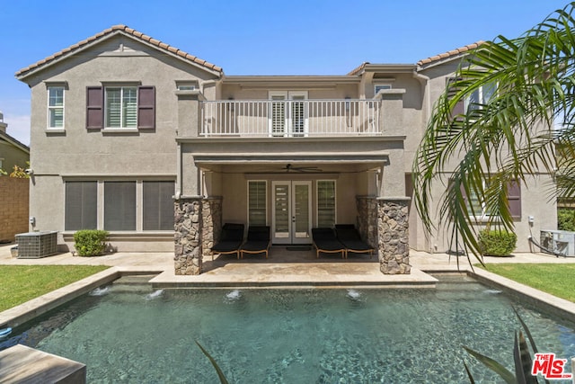 rear view of property featuring central AC, ceiling fan, a balcony, and french doors