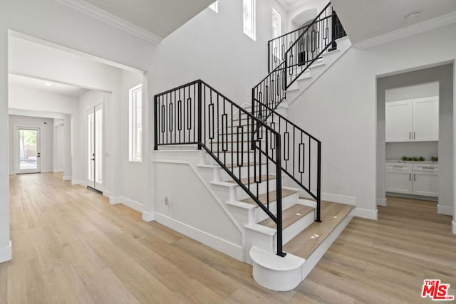 stairs featuring hardwood / wood-style floors and ornamental molding