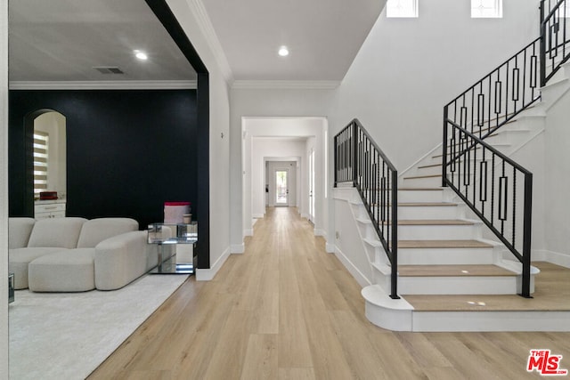 foyer entrance featuring crown molding and light hardwood / wood-style flooring