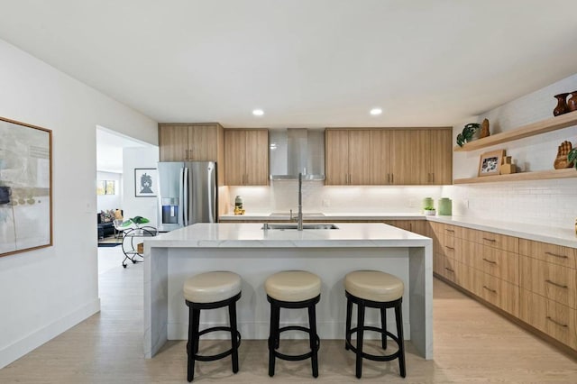 kitchen featuring a kitchen breakfast bar, stainless steel fridge with ice dispenser, a kitchen island with sink, and light hardwood / wood-style flooring