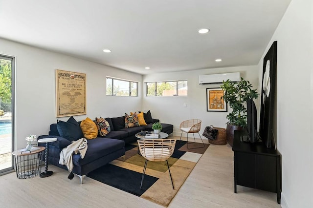 living room featuring a wall mounted air conditioner, light hardwood / wood-style floors, and a healthy amount of sunlight