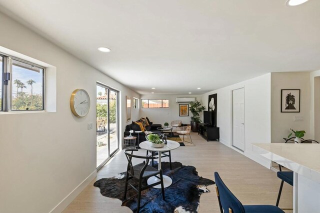 dining area featuring light wood-type flooring and an AC wall unit