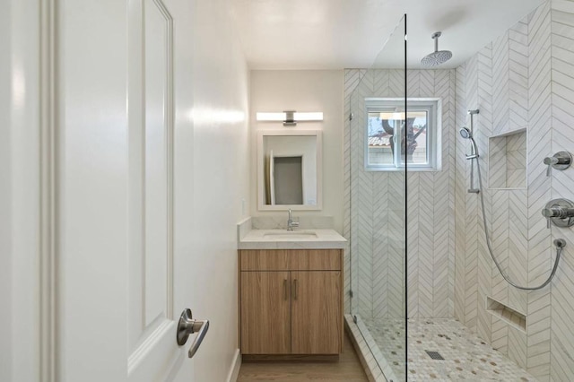 bathroom with a tile shower, vanity, and hardwood / wood-style flooring