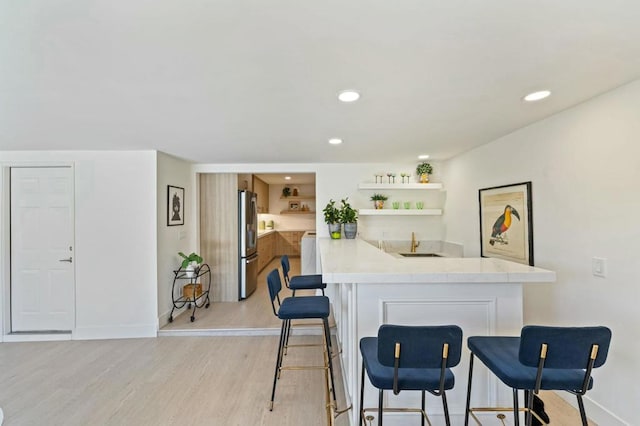 bar featuring stainless steel fridge, light wood-type flooring, and sink