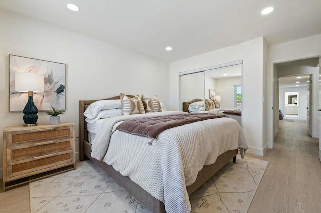 bedroom with light hardwood / wood-style floors and a closet