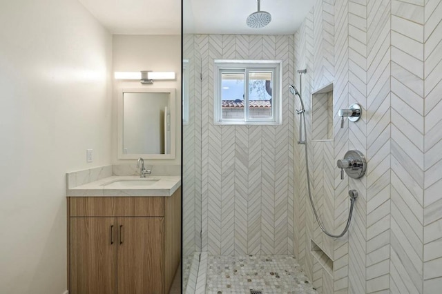 bathroom with a tile shower and vanity