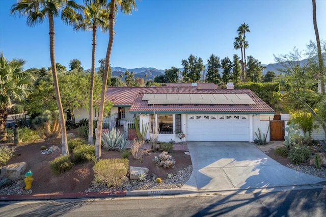 view of front of home with a mountain view, a garage, and solar panels