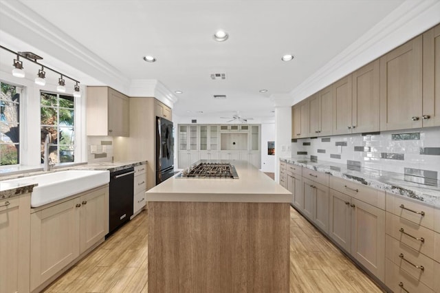 kitchen featuring a center island, black appliances, sink, light hardwood / wood-style flooring, and ceiling fan