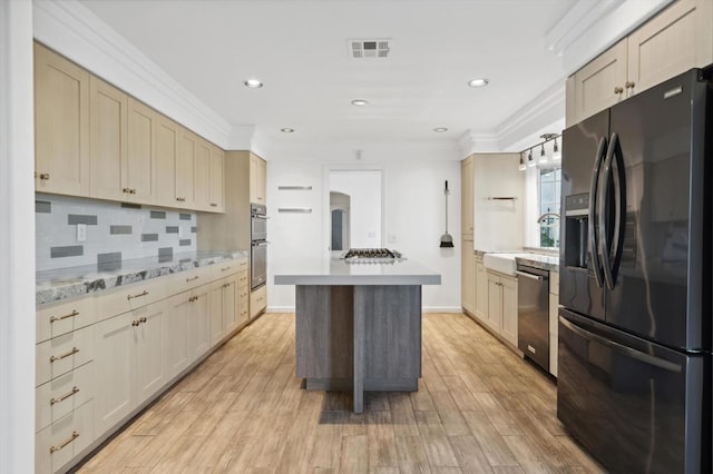 kitchen featuring a center island, backsplash, crown molding, appliances with stainless steel finishes, and light hardwood / wood-style floors