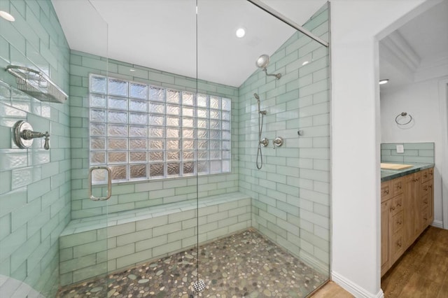 bathroom featuring hardwood / wood-style floors, vanity, lofted ceiling, and walk in shower