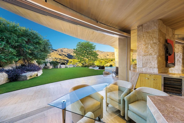 view of patio featuring a mountain view, an outdoor kitchen, and beverage cooler