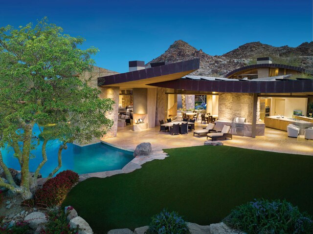 rear view of property featuring outdoor lounge area, a mountain view, a patio area, and an outdoor kitchen