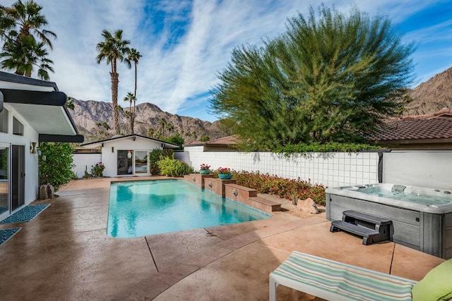 view of swimming pool featuring a mountain view, a patio area, an outbuilding, and a hot tub