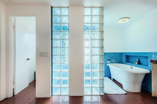 bathroom featuring a washtub, vanity, and tile walls