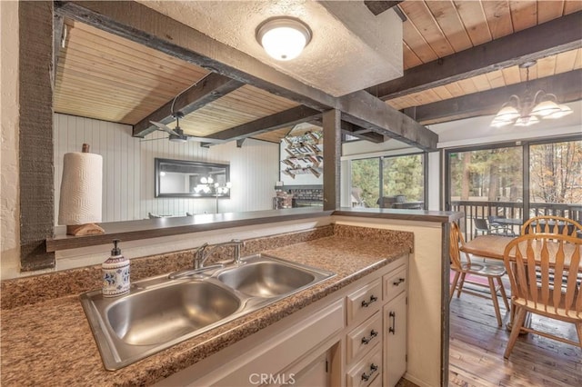 kitchen featuring beam ceiling, wooden ceiling, sink, and light hardwood / wood-style floors