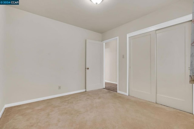 unfurnished bedroom featuring a closet and light colored carpet