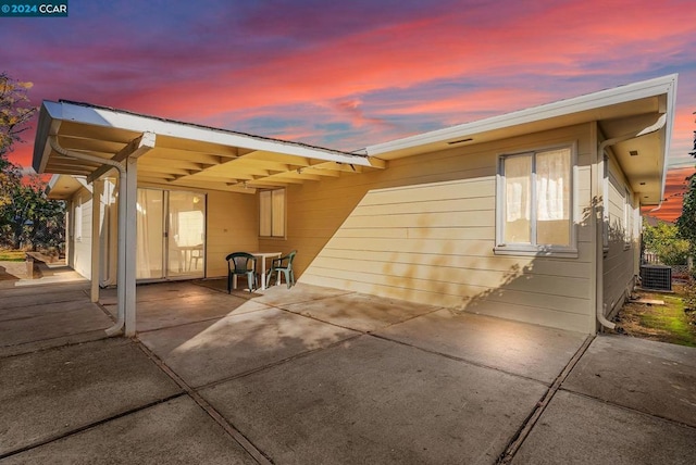 property exterior at dusk featuring a patio area and cooling unit