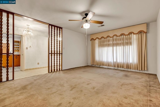 empty room featuring carpet and ceiling fan with notable chandelier