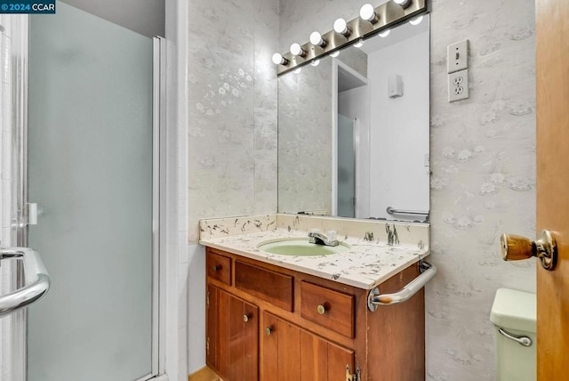 bathroom featuring vanity, toilet, and a shower with shower door