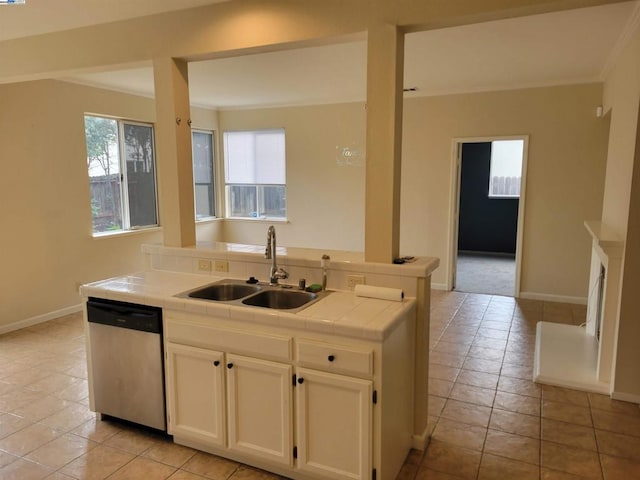 kitchen with light tile patterned floors, tile countertops, white cabinetry, stainless steel dishwasher, and sink