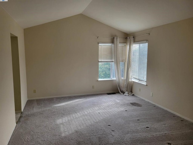 carpeted empty room with vaulted ceiling