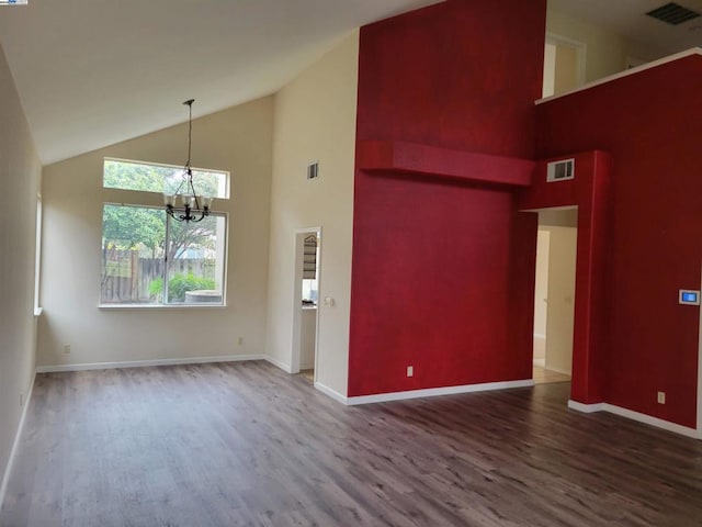 empty room with a high ceiling, wood-type flooring, and an inviting chandelier