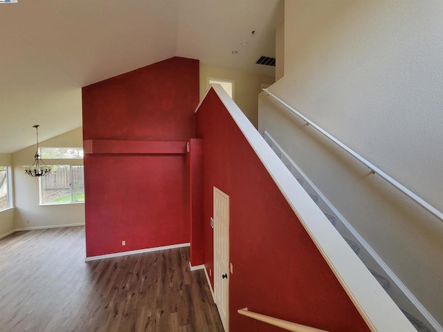 staircase featuring hardwood / wood-style floors, lofted ceiling, and an inviting chandelier