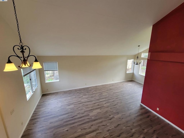 unfurnished living room featuring vaulted ceiling, hardwood / wood-style floors, and a notable chandelier