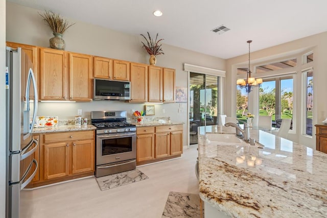 kitchen with an inviting chandelier, sink, light stone countertops, decorative light fixtures, and stainless steel appliances