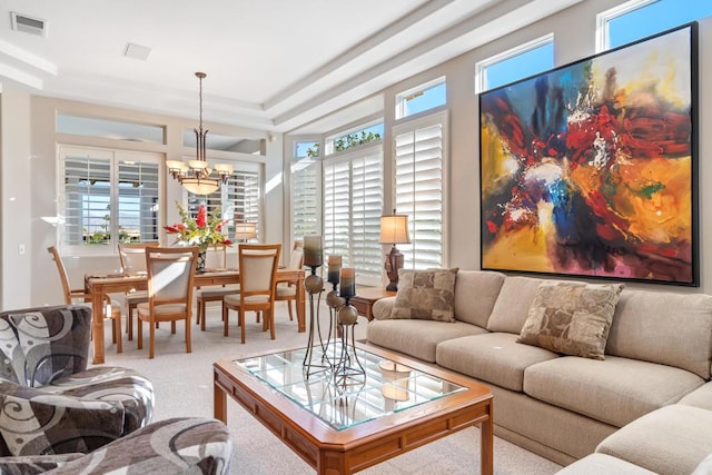 carpeted living room featuring a notable chandelier