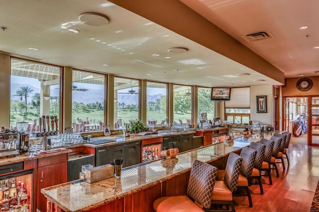 interior space with hardwood / wood-style floors, light stone countertops, and a breakfast bar area