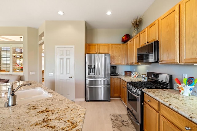 kitchen featuring light hardwood / wood-style floors, light stone counters, sink, and appliances with stainless steel finishes