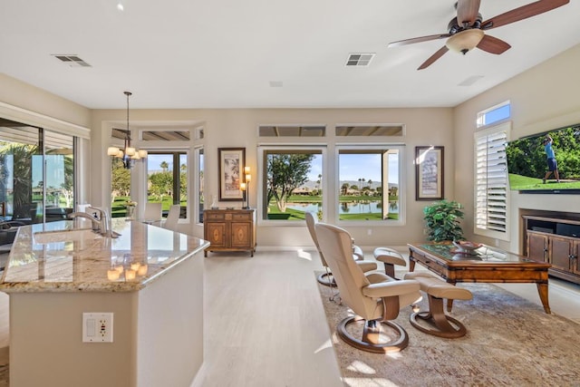 interior space with light stone countertops, pendant lighting, ceiling fan with notable chandelier, and plenty of natural light