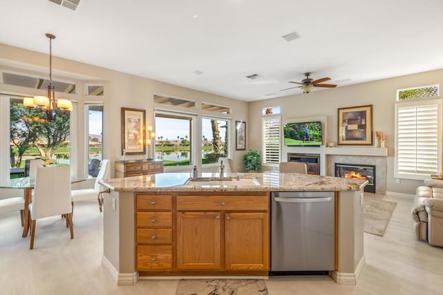 kitchen with sink, an island with sink, decorative light fixtures, a fireplace, and ceiling fan with notable chandelier