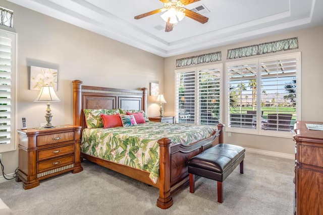 bedroom with ceiling fan, light carpet, and a tray ceiling