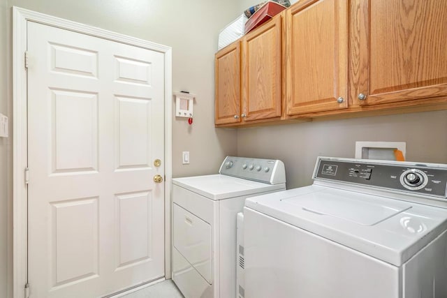 clothes washing area featuring washer and dryer and cabinets