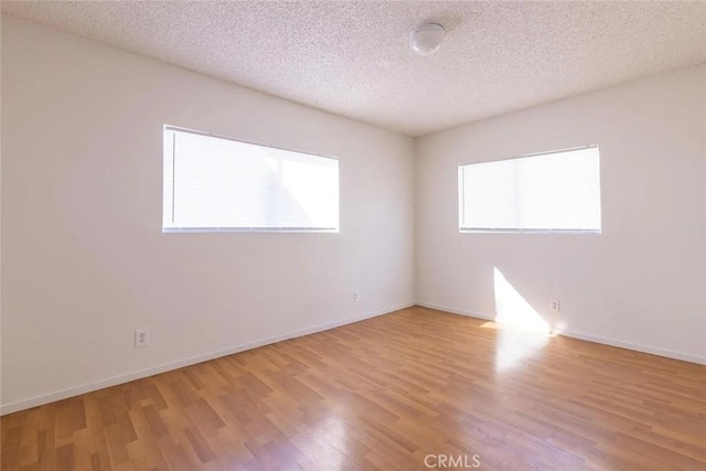 unfurnished room featuring a textured ceiling and light hardwood / wood-style flooring