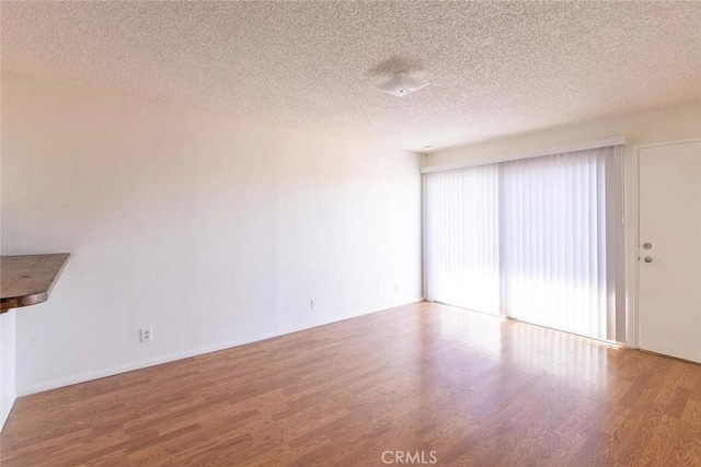 unfurnished living room featuring hardwood / wood-style floors and a textured ceiling