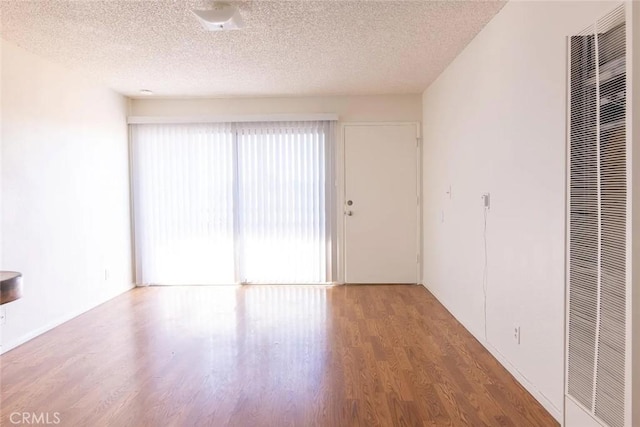 empty room with hardwood / wood-style floors and a textured ceiling