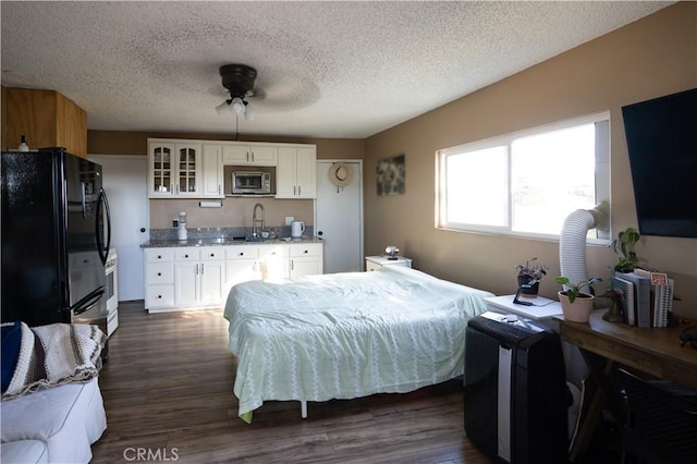 bedroom with dark hardwood / wood-style flooring, black fridge, a textured ceiling, ceiling fan, and sink