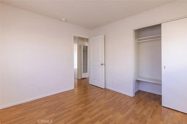 unfurnished bedroom with a textured ceiling, light hardwood / wood-style floors, and a closet