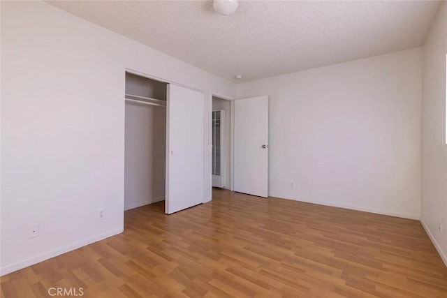 unfurnished bedroom with a textured ceiling, light hardwood / wood-style floors, and a closet